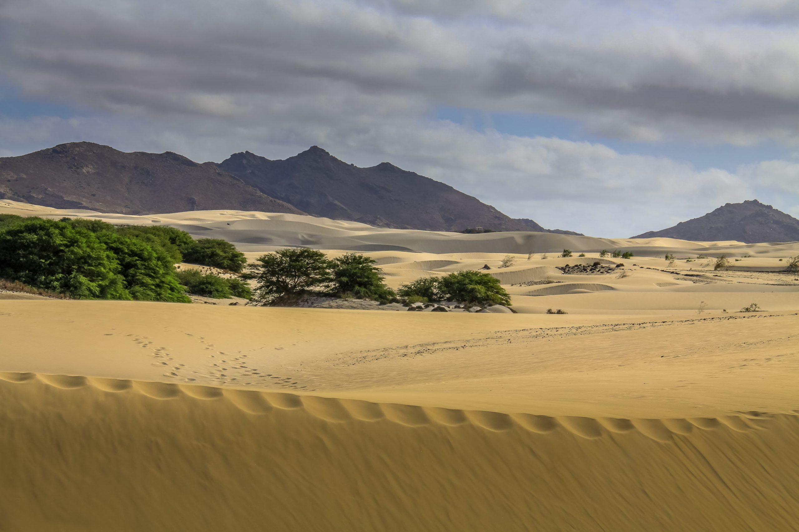 The desert sand with extinct volcanoes in the background, on Boa Vista, the capital of Cape Verde.